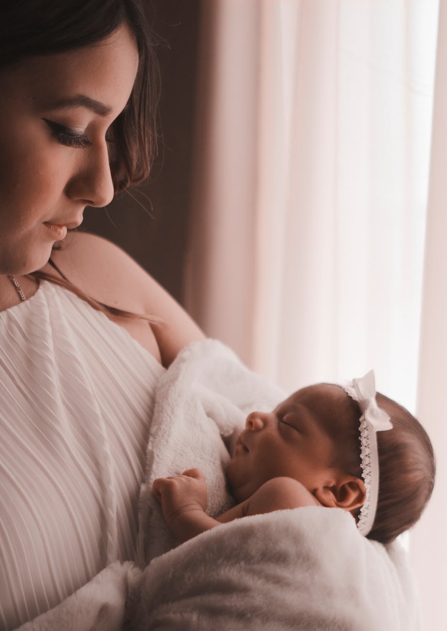 selective focus photography of woman carrying her cute baby