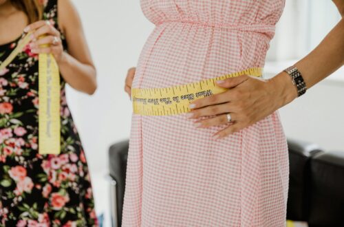 Close-up of a pregnant woman measuring her belly, symbolizing pregnancy health.